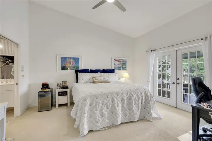 Carpeted Owners Suite featuring lofted ceiling, access to outside, connected bathroom, ceiling fan, and french doors