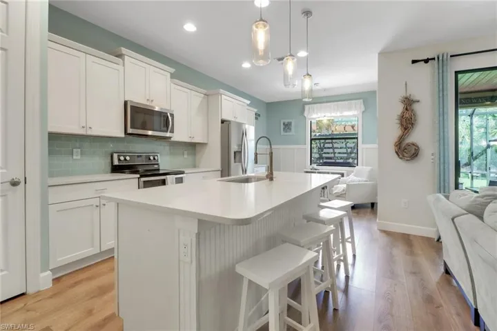 Kitchen with appliances with stainless steel finishes, light countertops, a kitchen island with sink, a breakfast bar area, and open floor plan