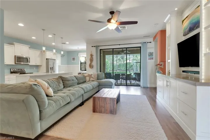 Living room with a ceiling fan, visible vents, wood finished floors, a wainscoted wall, and recessed lighting