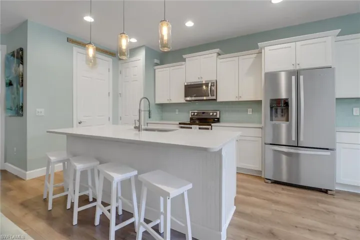 Kitchen featuring a sink, decorative backsplash, appliances with stainless steel finishes, and light wood-style flooring