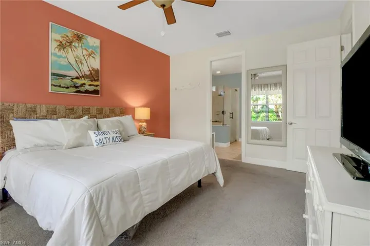 Bedroom with ceiling fan, light carpet, ensuite bath, and visible vents