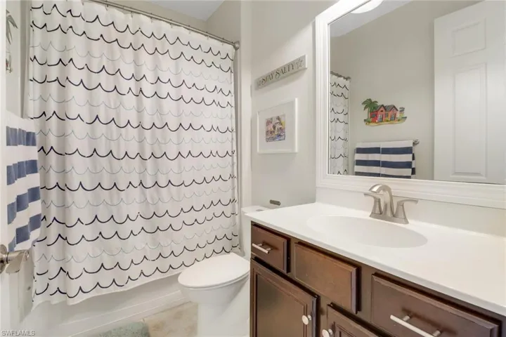 Bathroom with vanity, shower / tub combo with curtain, tile patterned flooring, and toilet