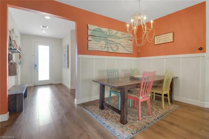 Dining area featuring an inviting chandelier, wainscoting, wood finished floors, and a decorative wall