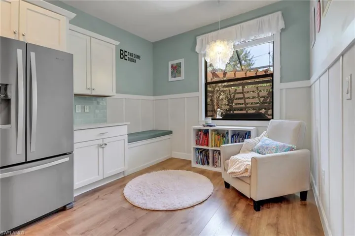 Sitting room featuring a decorative wall, a chandelier, light wood-style flooring, and a wainscoted wall