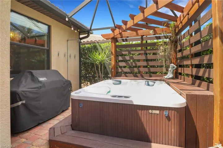 Wooden terrace with a hot tub, a pergola, and area for grilling