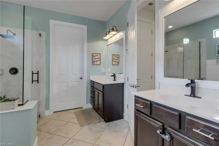 Bathroom featuring tile patterned flooring, a sink, and a shower stall