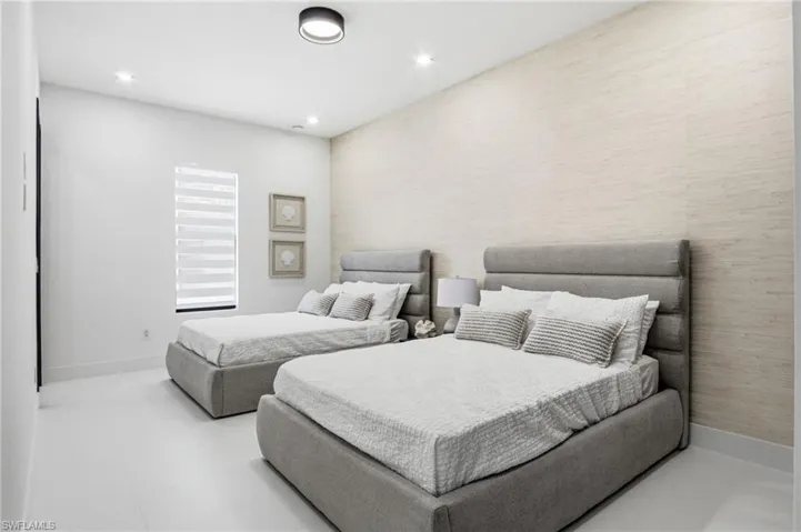 Bright bedroom featuring a textured accent wall and recessed lighting