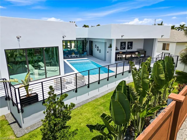 Modern exterior with expansive glass doors, a rectangular pool, and a structured outdoor kitchen