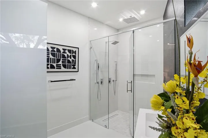Modern bathroom featuring a frameless glass shower enclosure, a rainfall showerhead, and a recessed shower niche