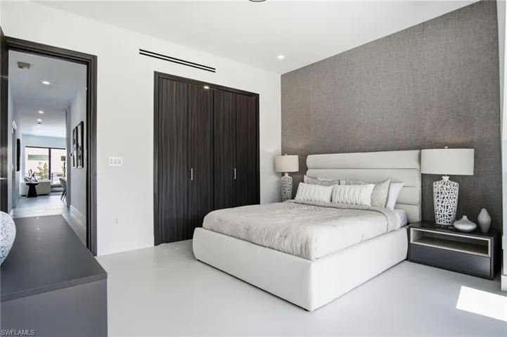 Bedroom featuring a textured accent wall, dark wood-finish bi-fold closet doors, recessed lighting, and light-toned flooring