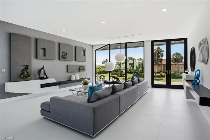 Spacious living area featuring large format light-toned flooring, expansive glass doors, recessed lighting, and a contemporary built-in wall unit