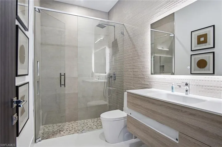Walk-in shower with clear glass enclosure, pebble-style flooring, and integrated bench seating