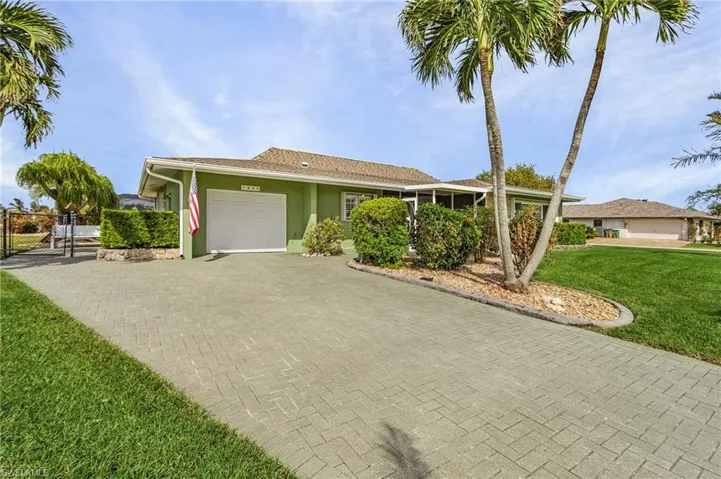 View of front facade with beautifully maintained  lawnl and oversized garage and pavered driveway and side patio