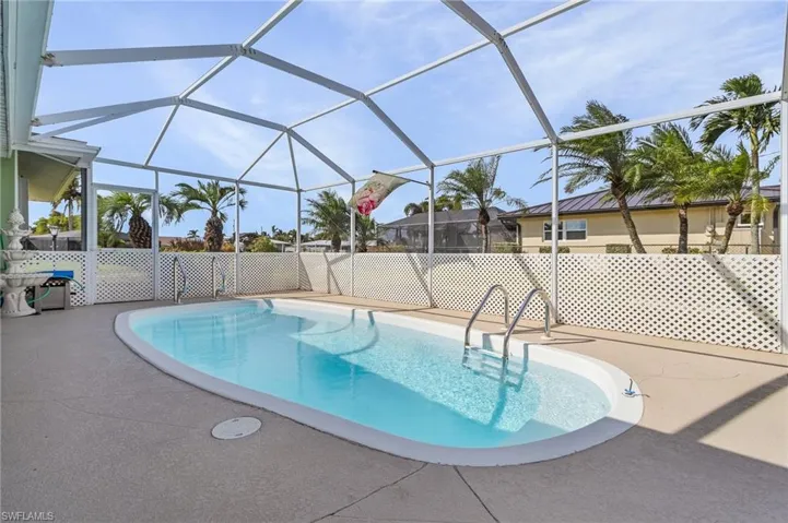 View of heated pool featuring a patio and screen enclosure with privacy lattice over screen