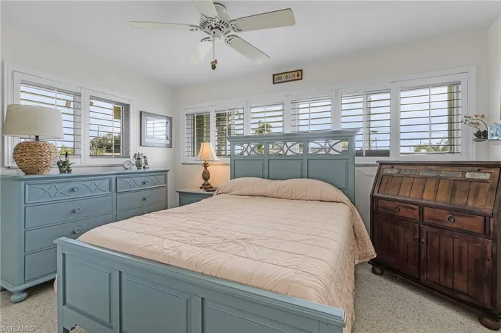 Bedroom with ceiling fan located on the SW corner of the home with large double closet and plantation shutters and terrazo floors