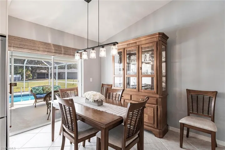 Tiled dining space featuring vaulted ceiling