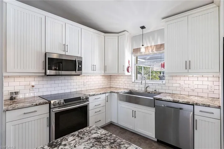 Kitchen featuring sink, stainless steel appliances, decorative light fixtures, and white cabinets