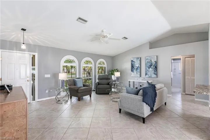 Tiled living room with ceiling fan and vaulted ceiling