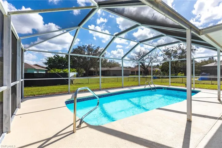 View of swimming pool with a patio area, a yard, and screen enclosure