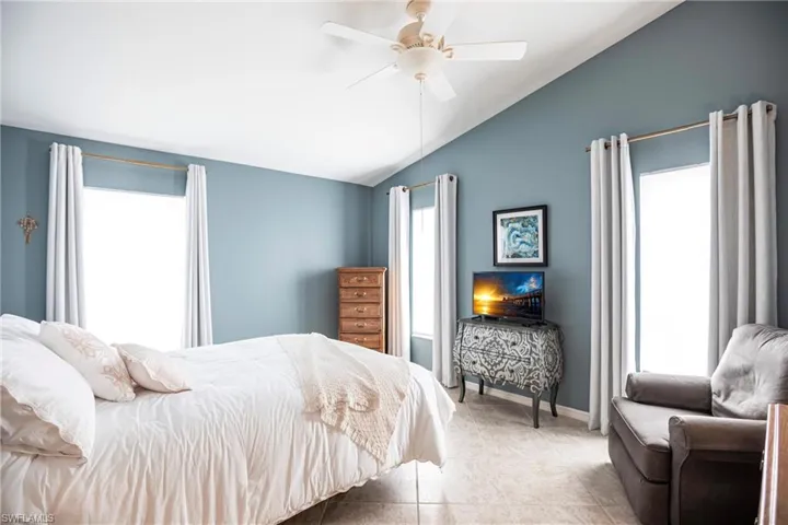 Primary Bedroom with ceiling fan, vaulted ceiling, and multiple windows