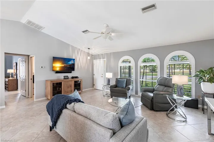 Living room with vaulted ceiling, light tile patterned flooring, and ceiling fan