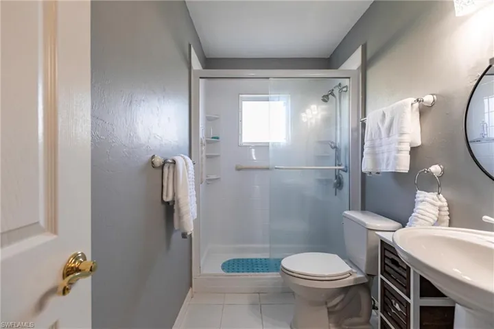 Guest Bathroom with toilet, sink, tile patterned flooring, and an enclosed shower