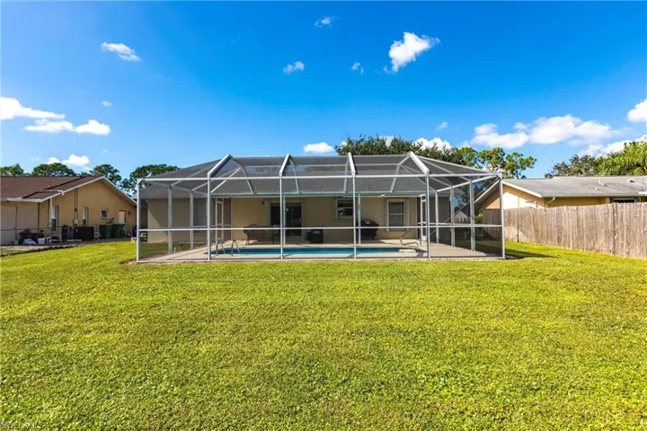 Rear view of property with a fenced in pool, a lanai, a patio, and a lawn