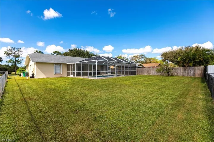 Rear view of property with a fenced in pool, a lanai, and a lawn