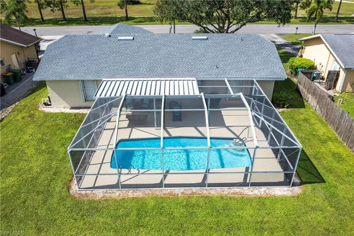 View of swimming pool with a patio, a yard, and glass enclosure