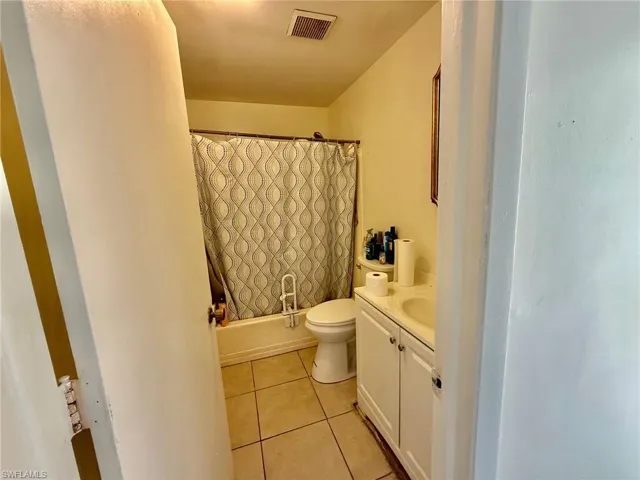 The bathroom features a vanity with cabinet storage, a toilet, and a shower/tub combination with a patterned shower curtain