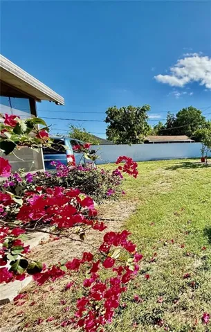 The property features a green lawn area and vibrant red and purple flowering plants