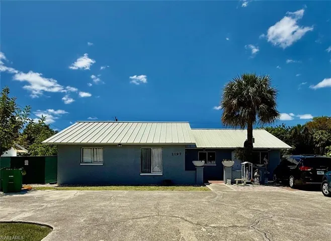 The property features a light-colored metal roof and a paved driveway