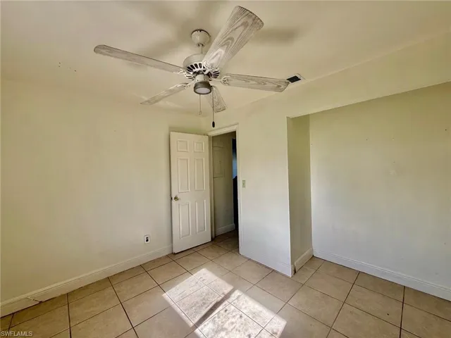 This room features tiled flooring, light-colored walls, and a ceiling fan with light-colored blades