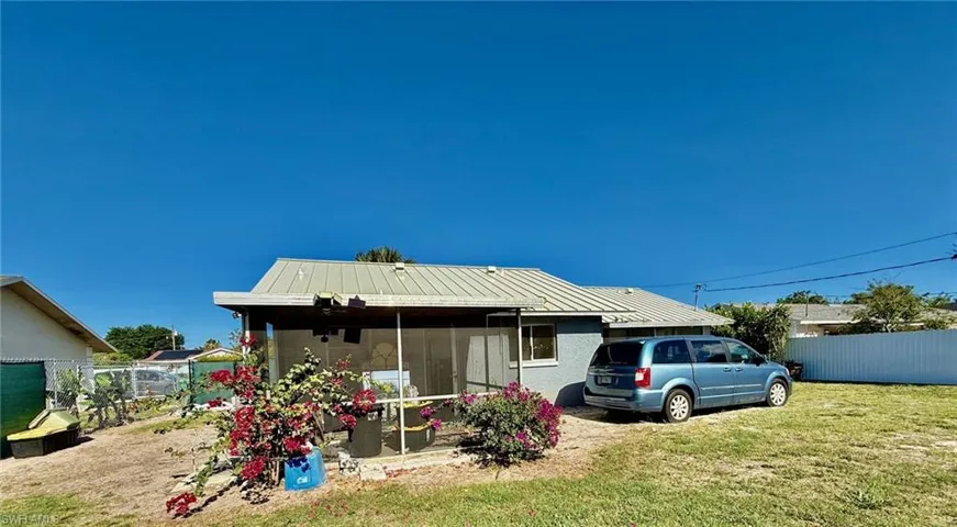 The property features a screened-in porch, a light grey exterior, and a metal roof