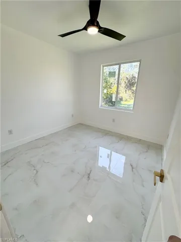 Empty room featuring light marble finish floors and ceiling fan