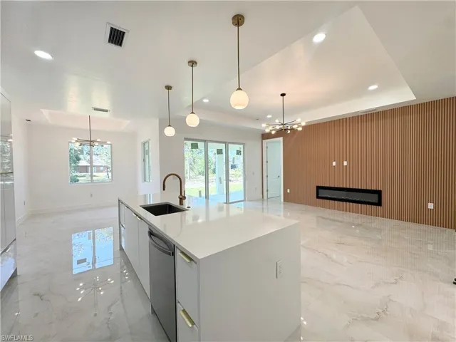 Kitchen with a chandelier, wooden walls, open floor plan, an accent wall, and recessed lighting