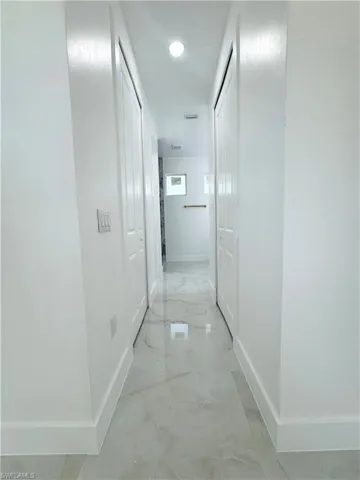 Corridor featuring light marble finish floors and recessed lighting