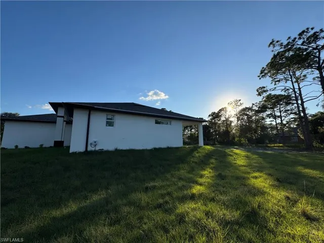 Back of property with a yard and stucco siding