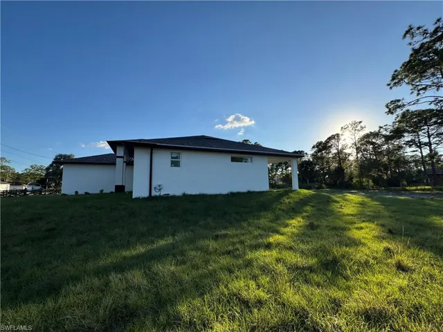 Back of house with a lawn and stucco siding