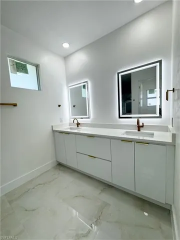 Full bathroom featuring light marble finish floors, double vanity, and recessed lighting