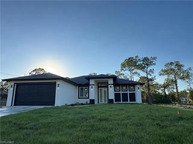 Prairie-style home with a front yard, stucco siding, concrete driveway, and an attached garage