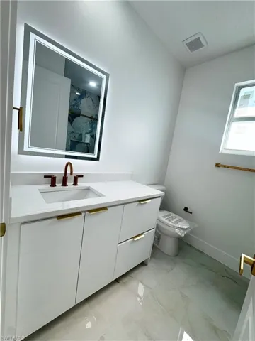 Bathroom featuring a marble finish shower, vanity, and light marble finish floors