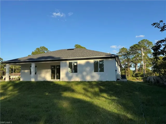 Back of property with a yard and stucco siding