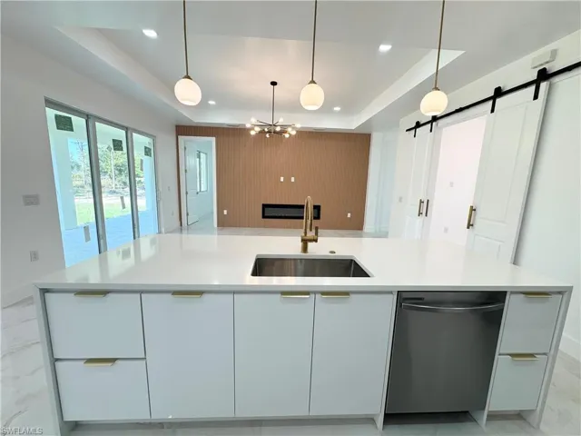 Kitchen with modern cabinets, a tray ceiling, white cabinets, hanging light fixtures, and recessed lighting