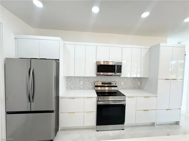 Kitchen featuring appliances with stainless steel finishes, modern cabinets, white cabinetry, and recessed lighting