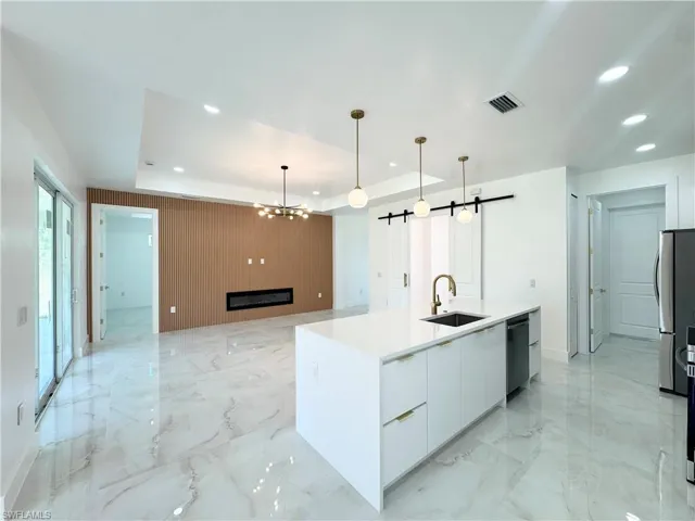 Kitchen featuring modern cabinets, a barn door, white cabinetry, recessed lighting, and a glass covered fireplace