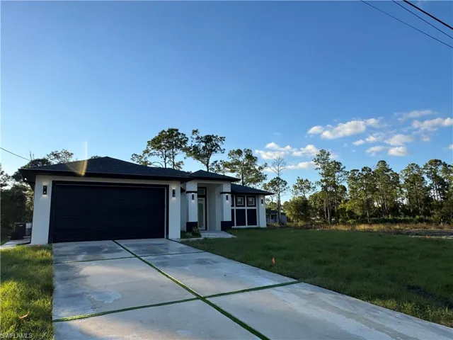View of front facade with concrete driveway, a front yard, a garage, and stucco siding