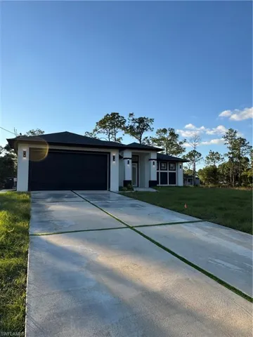 Prairie-style home with driveway, a front lawn, stucco siding, and an attached garage