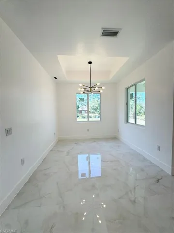 Unfurnished room featuring a chandelier and a tray ceiling