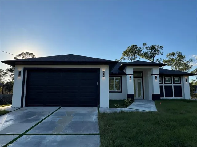 Prairie-style home featuring a front lawn, concrete driveway, stucco siding, and a garage